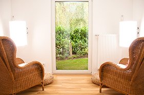 Zwei Korbsessel vor der offenen Tür zum Garten